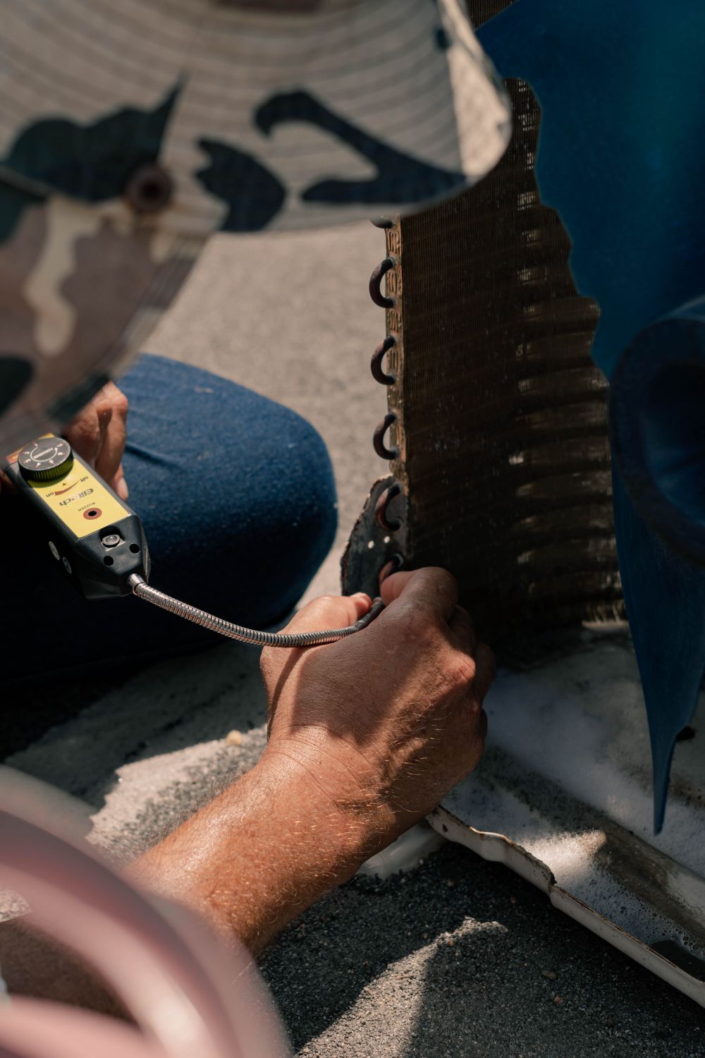 Close-up of a technician checking an air-conditioner coil with a meter